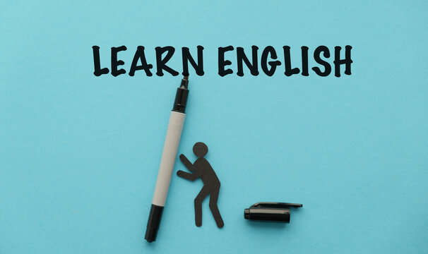 Learn English text on a blue background with a black paper person figure and a marker. A conceptual image for language learning, international education, ESL (English as a Second Language) classes