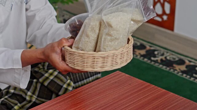 Close-up of hands giving basket of rice and dates for Zakat Al-Fitr