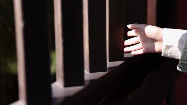 Finger woman gently brushes sliding across old wooden door window railing, Female hand touching hard rough wood on sunny summer day, revealing the changing light and shadow