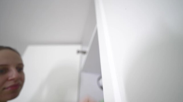 Woman performing spring cleaning at home, using a microfiber brush to wipe and dust surfaces, illustrating household chores, home hygiene, and domestic maintenance.