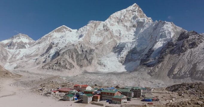 Aerial drone of Gorakshep settlement along the Everest Base Camp trail with Khumbu Glacier and Everest, Nuptse, and Lhotse himalayas mountain snow-capped peaks beneath a clear blue sky in Nepal.