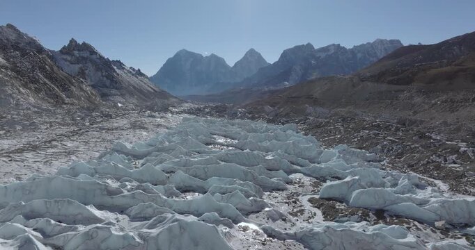 Cruising above frozen ice tower rising from Khumbu Glacier surrounded by dry rocky Himalayan mountains under clear high-altitude light in the Everest region of Nepal.