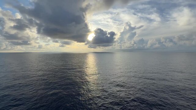 POV pan right from bow of ship across calm seas in the Mozambique Channel with the French Comoros in the distance with stratocumulus clouds at sunrise