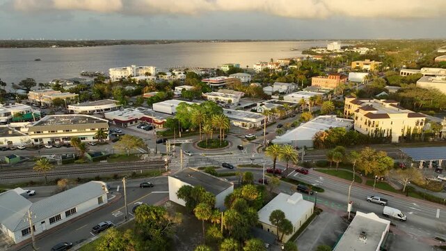 A cinematic drone view captures downtown Stuart, Florida glowing in warm sunset light beside the calm waters of the St. Lucie River.