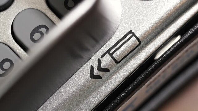 Angled close up of credit card swiped through payment terminal