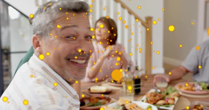 Man reaching drink, turning to camera, raising glass, toasting meal as yellow dots crossing frame