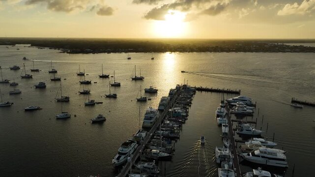 A cinematic drone view captures boats and sailboats anchored at Sunset Bay Marina as the sun sets over the waterways of Stuart, Florida.