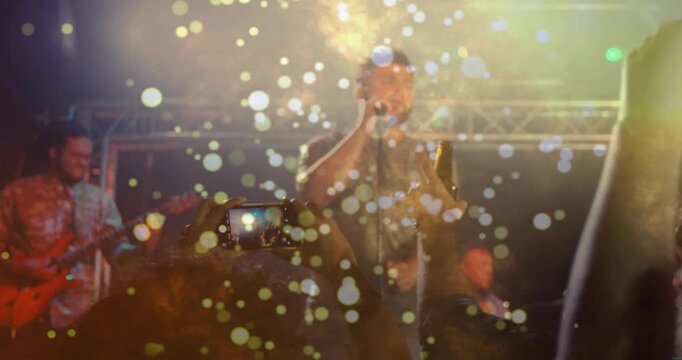 Fan raising phone sparking crowd recording as lead singer singing drifting bokeh obscuring faces