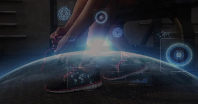 Woman in gym preparing to move, tying shoelaces while HUD icons Earth horizon pulsing over shoes