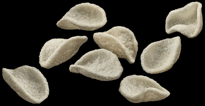 Falling japanese prawn crackers isolated on black background, traditional Asian snack, full depth of field