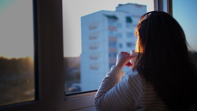 Woman Relaxing Indoors Looking Out Window at Sunset, have fun and enjoy