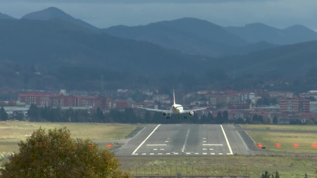 Airplanes landing at Bilbao Airport during strong southern winds. Aircraft move noticeably while touching down on the runway, illustrating challenging weather conditions and aviation operations.