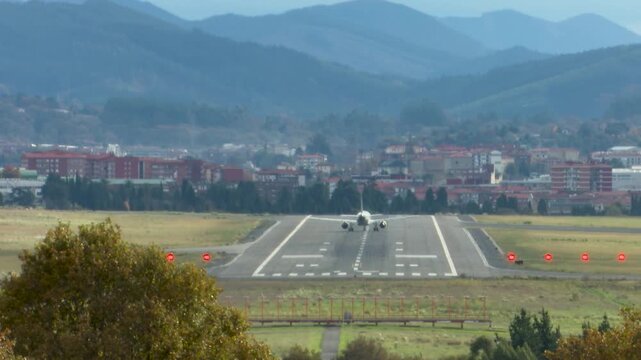 Airplanes landing at Bilbao Airport during strong southern winds. Aircraft move noticeably while touching down on the runway, illustrating challenging weather conditions and aviation operations.