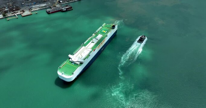 Large Vehicle Carrier Ship Navigating Coastal Waters With Tug Boat Assistance For Global Maritime Logistics