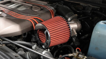 Naklejka premium Close up of a high performance red cone air intake filter in a modified car engine bay