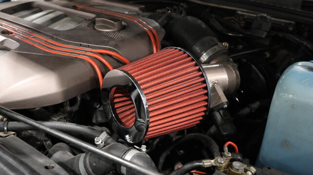 Close up of a high performance red cone air intake filter in a modified car engine bay