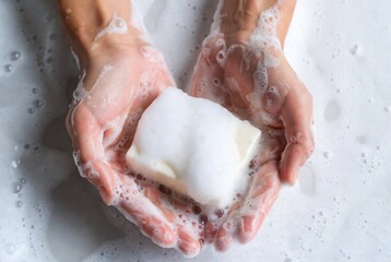 Fototapeta premium Hands holding a bar of soap in a bathtub. Washing hands. Bathroom.