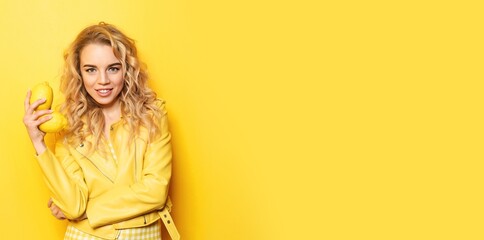 Fototapeta premium Portrait of beautiful young woman holding lemons on yellow background with space for text