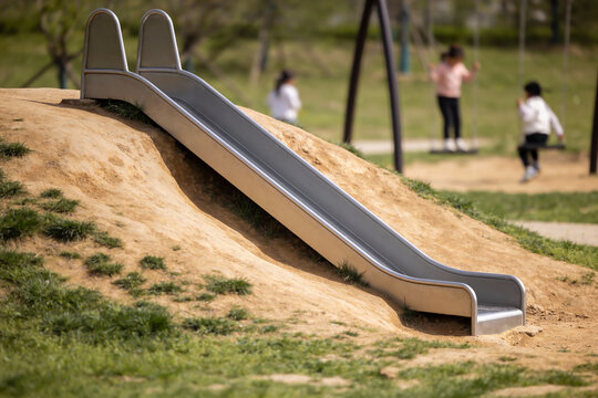 Children enjoying a sunny day on a playground slide and swings in the park