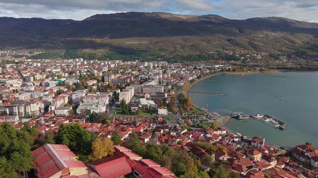 Drone footage of Ohrid&rsquo;s old town with Lake Ohrid and scenic landscape in the background, gradually revealing Varosh hill and showcasing the historic Balkan cityscape from above.