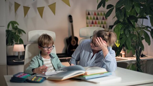 A woman helping her son with homework and check it, both are really tired of it