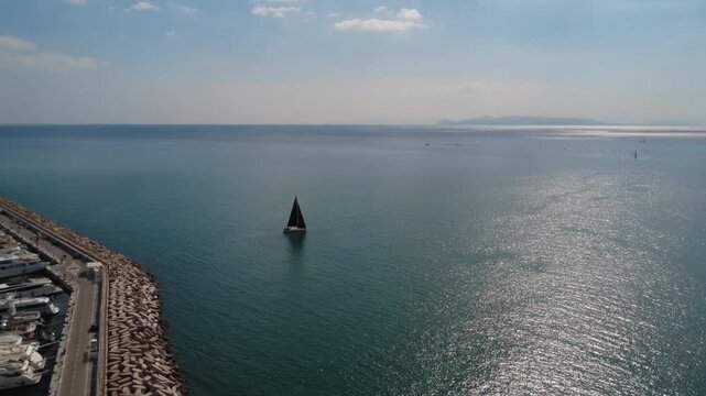 Lone sailing boat with black sails in deep blue sunset sea view