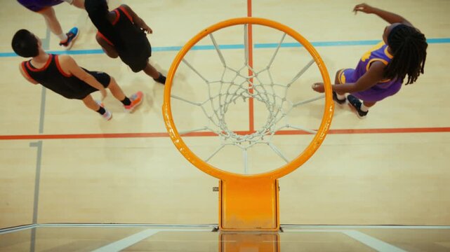 An overhead view captures a basketball soaring through a net, scoring a perfect shot. Players move on the court, showcasing sport, precision, and the excitement of the game.