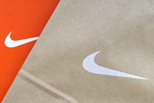 Nike logo displayed on an orange box next to the logo on a paper bag. Nike is an American sportswear company.