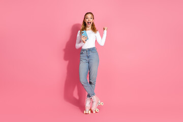 Joyful young woman posing in stylish casual attire on roller skates while expressing surprise...