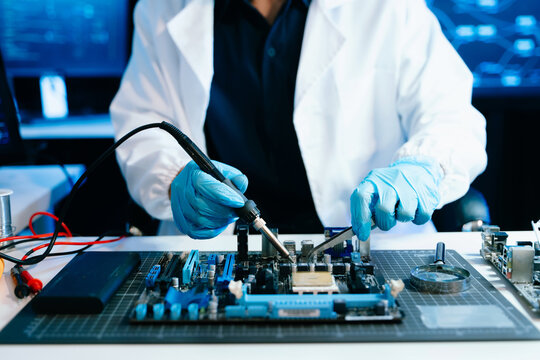 Technician repairing computer motherboard with soldering tools in a high-tech laboratory, focusing on electronics engineering, hardware diagnostics, cybersecurity systems