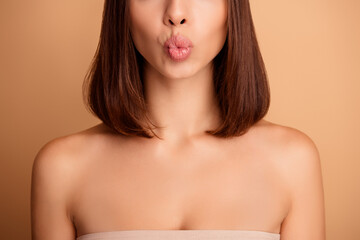 Chic young woman with smooth tanned skin poses with puckered lips showcasing beauty care and...