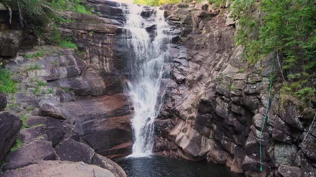 Scenic view of natural waterfall in lush green Norwegian forest. Flowing water, rocky stream, and peaceful surroundings promote eco tourism, relaxation, and nature-inspired travel lifestyle.