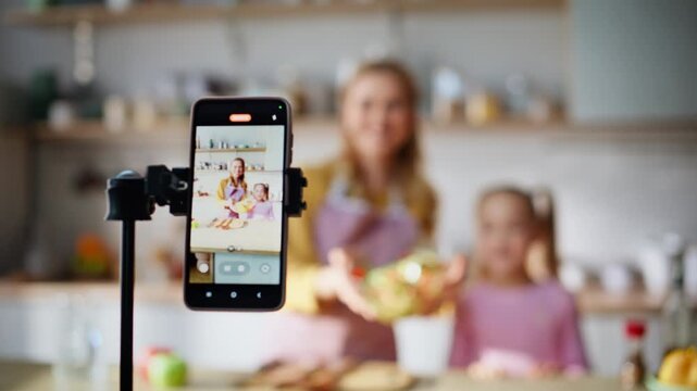 Mother child bloggers cooking live speaking cellphone camera kitchen closeup