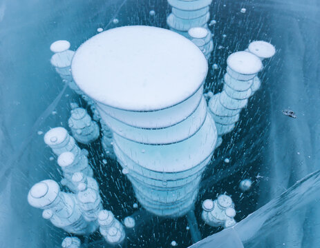 Bulles de m&eacute;thane gel&eacute;es emprisonn&eacute;es dans les couches d'un lac gel&eacute; transparent, formes disco&iuml;des blanches empil&eacute;es &agrave; diff&eacute;rentes profondeurs dans une glace bleue