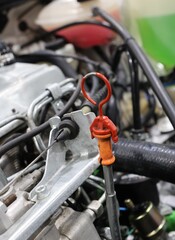 Fototapeta premium Close up of an orange engine oil dipstick handle in a car engine bay