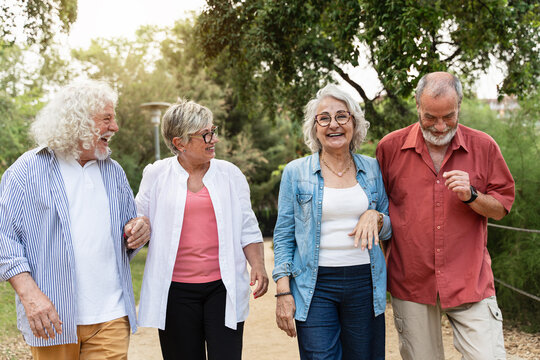 Happy senior friends walking together in park enjoying retirement lifestyle and friendship