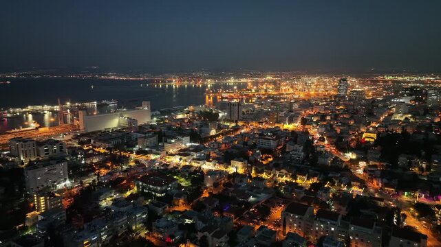 Aerial night view of Haifa with the Baha'i Gardens, German Colony, and the illuminated city port, Israel