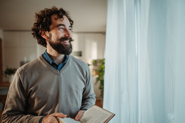 Fototapeta premium Happy man reading book looking out window