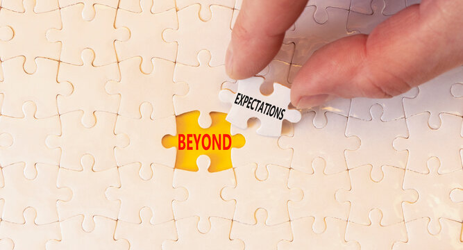 Beyond expectations words symbol. Concept words Beyond expectations on beautiful white puzzles. Beautiful yellow background. Businessman hand. Business Beyond expectations words concept. Copy space.