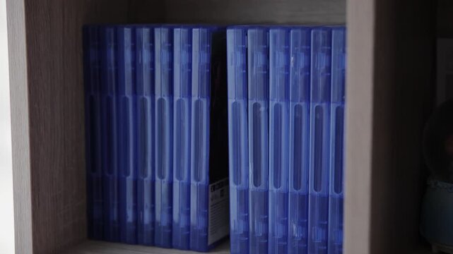 Woman Choosing a Video Game Blue Case from a Shelf to Play on Console