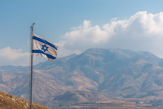 The Israeli flag waves proudly against a backdrop of rugged mountains and a cloudy sky