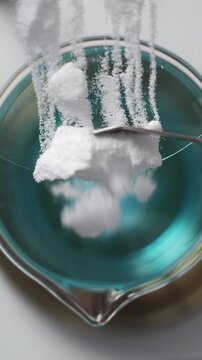 Chemical reaction dissolving white powder into a blue liquid in a scientific laboratory beaker creating a solution