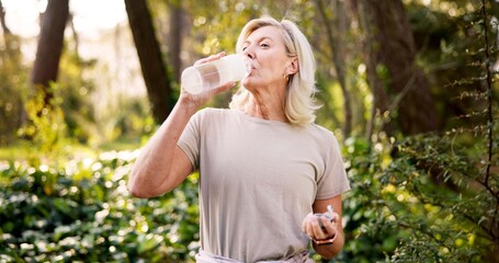 Obraz premium Hiking, drinking water and mature woman in forest for adventure guide, wildlife conservation and trekking. National park, environment and wellness with person explore in nature for field research