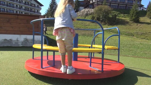 Child Playing on Roundabout at Playground, Girl Spinning, Kid Rotating on a Merry-Go-Round, Children