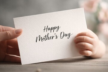 Obraz premium Elegant Happy Mother’s Day card in cursive typography held by a baby's hand and an adult's hand, concept of maternal love, family tenderness, Mother's Day celebration