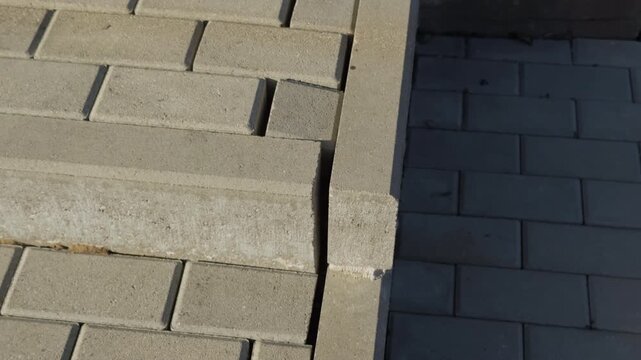 Cracked curb surface under sharp afternoon sunlight. Detailed view of fractured concrete edge and textured surface in natural lighting
