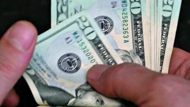 Man counting stack of 20 dollar bills, cash money and financial concept close up