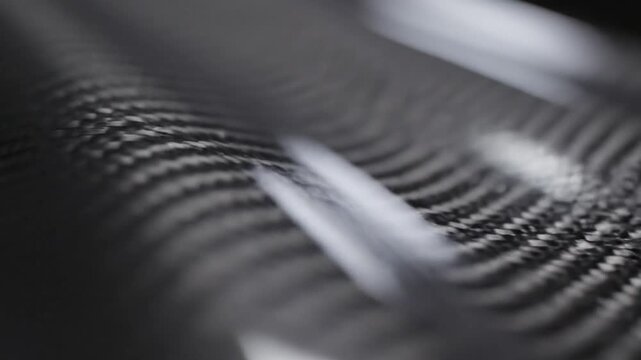 Close-up of carbon fiber weave texture, black and grey.