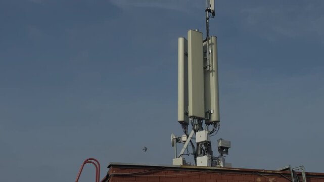 Urban rooftop communication equipment. Cellular transceivers set up on city roof with safety measures and maintenance indication