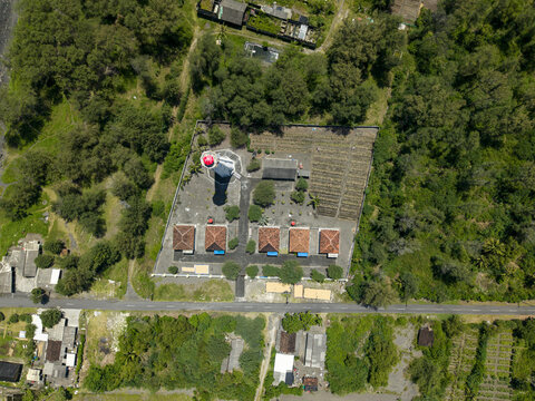 Aerial view of the Mercusuar Samas lighthouse standing tall amidst lush greenery and modest buildings, a coastal beacon, Bantul Regency, Indonesia.